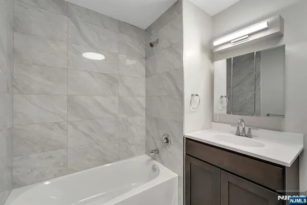 a bathroom with a bathtub shower sink vanity and a mirror