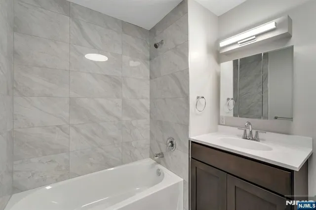 a bathroom with a bathtub shower sink vanity and a mirror