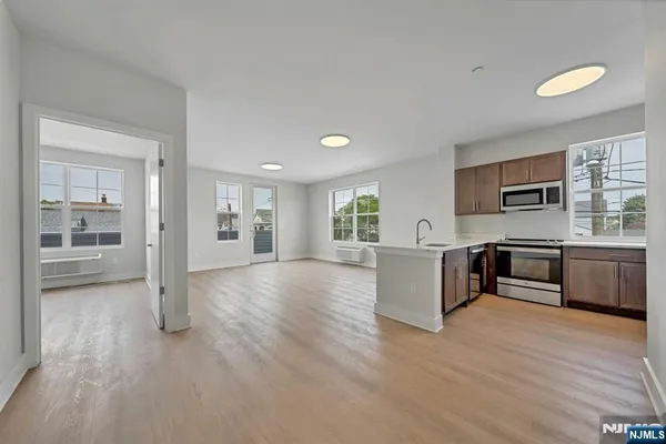 a view of kitchen with stainless steel appliances granite countertop a stove top oven a sink dishwasher a refrigerator and cabinets with wooden floor