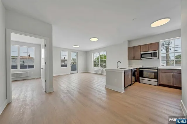 a view of kitchen with stainless steel appliances granite countertop a stove top oven a sink dishwasher a refrigerator and cabinets with wooden floor