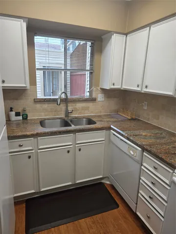 a kitchen with granite countertop white cabinets sink and window