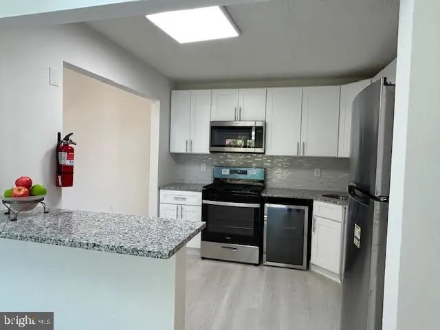 a kitchen with granite countertop a sink dishwasher a stove and a microwave oven with cabinets