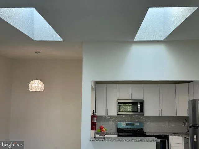 a kitchen with stainless steel appliances a sink a stove top oven a counter space and cabinets