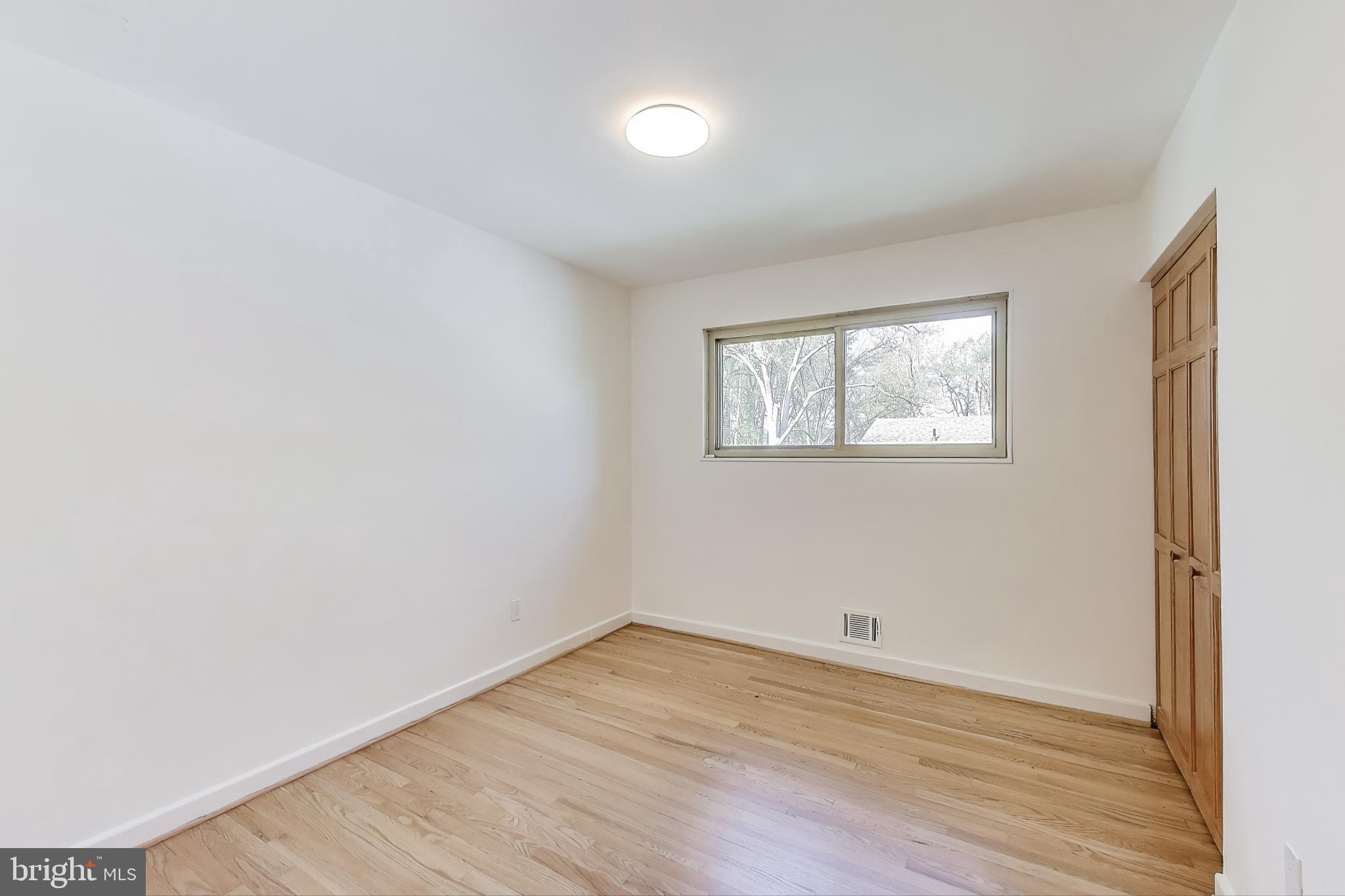 8905 Spring Valley Road Chevy Chase, MD 20815 - Photo 17 of 42 an empty room with wooden floor and windows