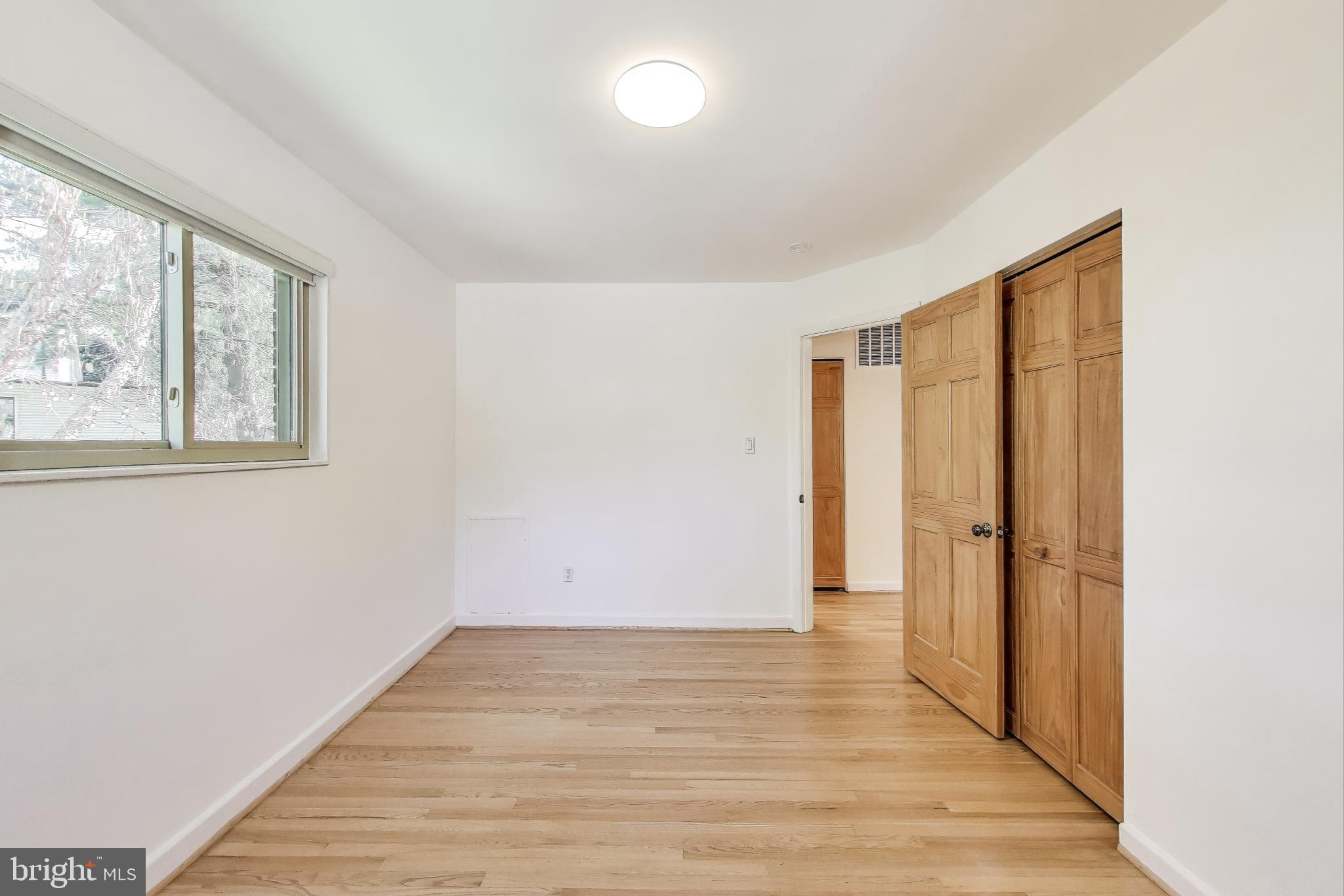 8905 Spring Valley Road Chevy Chase, MD 20815 - Photo 20 of 42 an empty room with wooden floor and windows