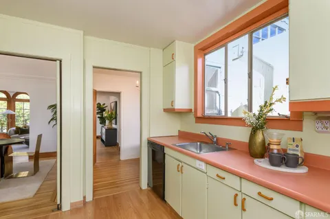a kitchen with sink and view of wooden floor