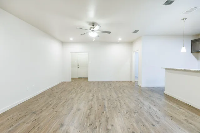 an empty room with wooden floor and fan