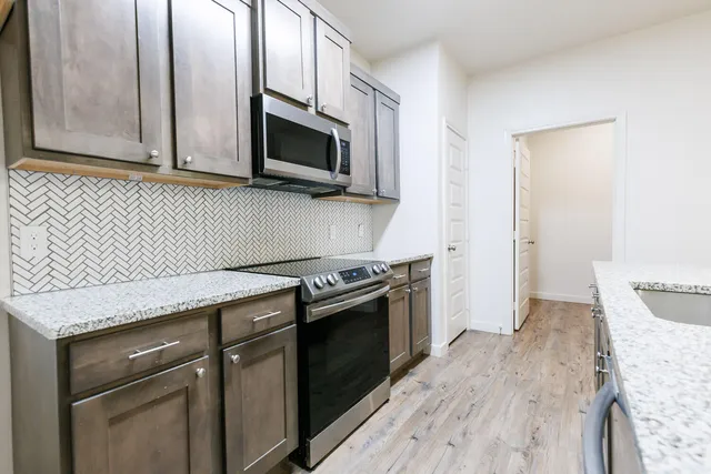 a kitchen with stainless steel appliances granite countertop a stove microwave and sink