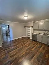 a view of a electric appliances in kitchen and empty room with wooden floor