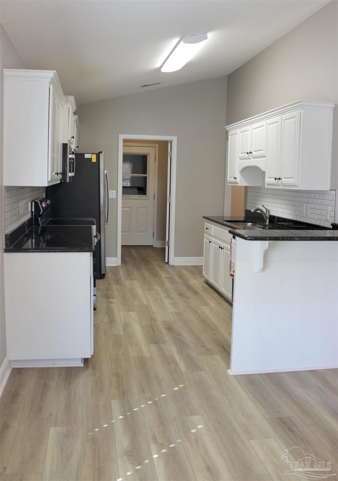 6364 Parakeet Trail Pensacola, FL 32503 - Photo 25 of 72 a kitchen with stainless steel appliances a stove a microwave a sink and white cabinets