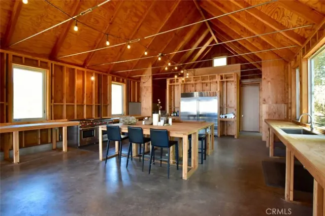 a large kitchen with stainless steel appliances wooden floor and a view of living room