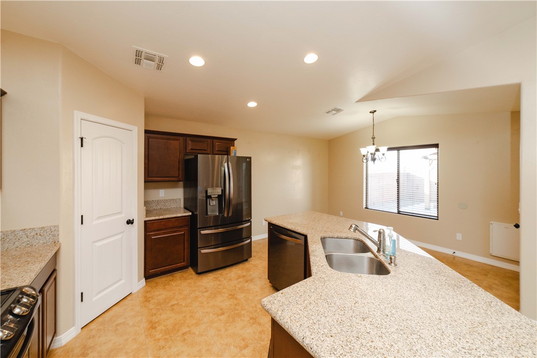 3379 Motherload Road Kingman, AZ 86401 - Photo 20 of 67 Kitchen featuring stainless steel appliances, decorative light fixtures, light stone counters, recessed lighting, and dark brown cabinets