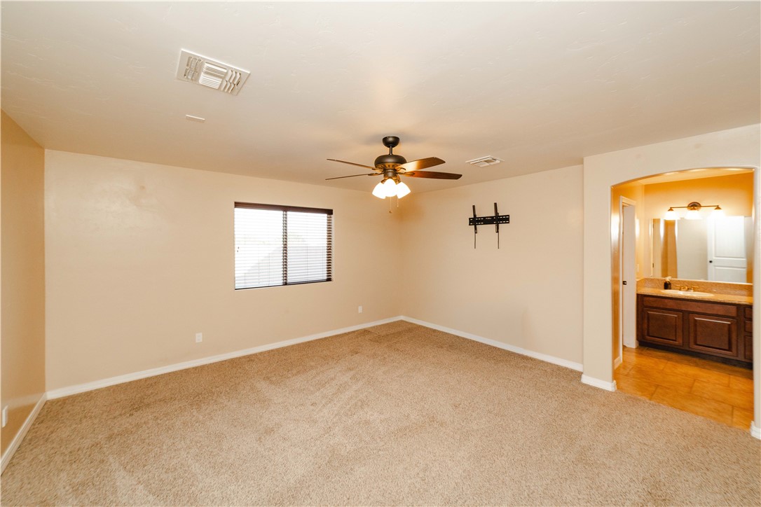 3379 Motherload Road Kingman, AZ 86401 - Photo 21 of 67 Unfurnished bedroom featuring arched walkways, light carpet, ensuite bathroom, and ceiling fan