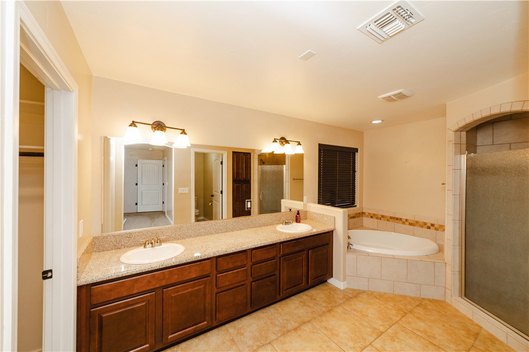 3379 Motherload Road Kingman, AZ 86401 - Photo 25 of 67 Bathroom featuring double vanity, a bath, a stall shower, light tile patterned floors, and a spacious closet