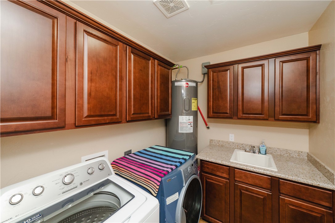 3379 Motherload Road Kingman, AZ 86401 - Photo 39 of 67 Laundry area featuring cabinet space, water heater, and washing machine and dryer and sink area