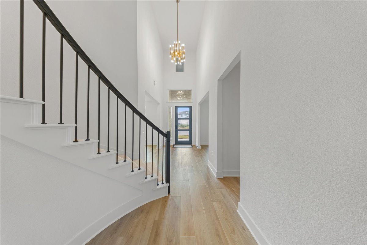 8700 Olmsted Way Austin, TX 78744 - Photo 22 of 40 Entrance foyer featuring light wood finished floors, a towering ceiling, stairs, and a chandelier