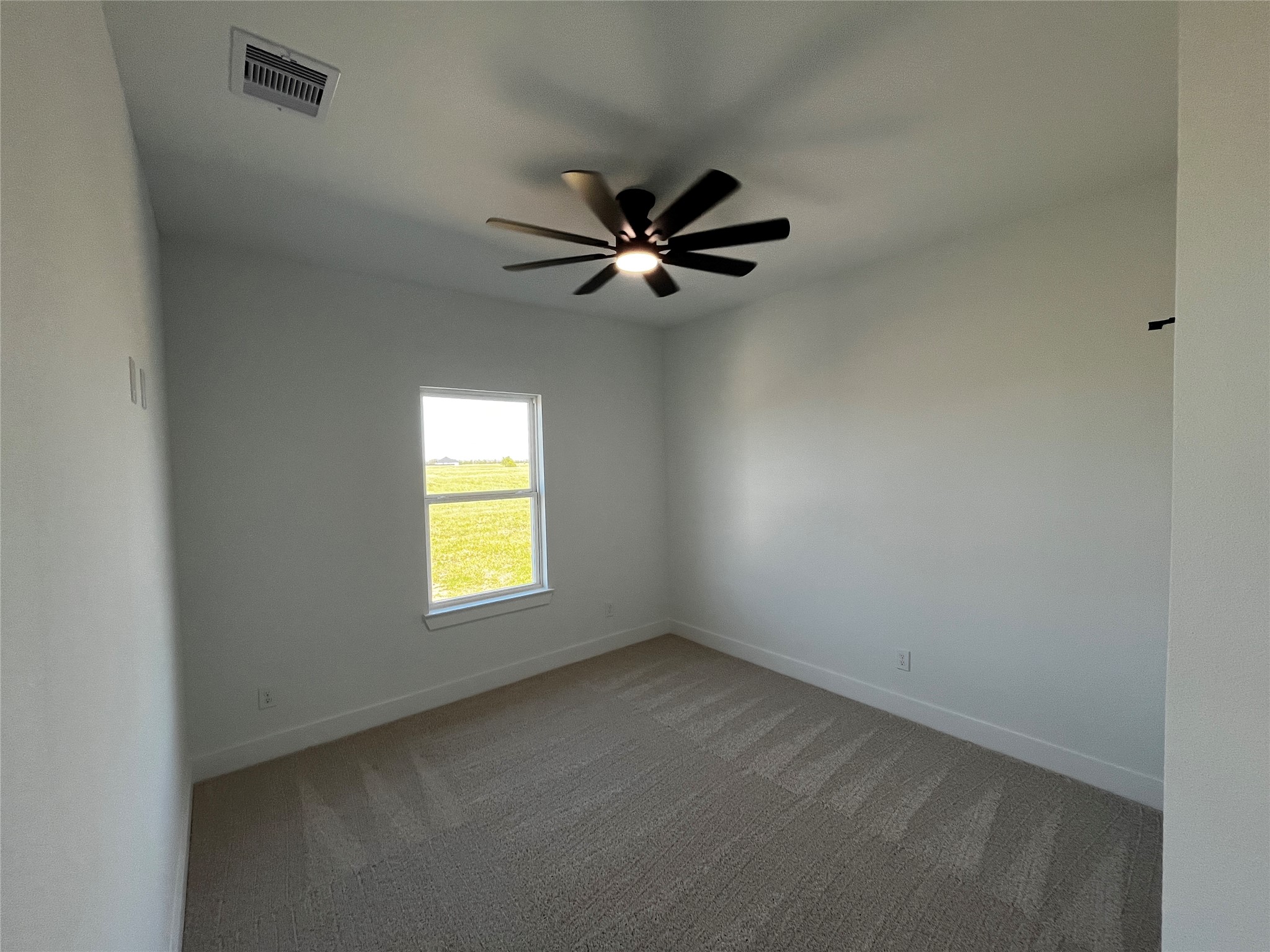 471 Buffalo Trail Angleton, TX 77515 - Photo 18 of 35 The secondary room features neutral walls, a ceiling fan, and a window with a view of a grassy outdoor area, creating a bright and airy space.
