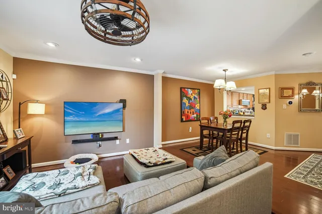 a living room with furniture and a flat screen tv with kitchen view