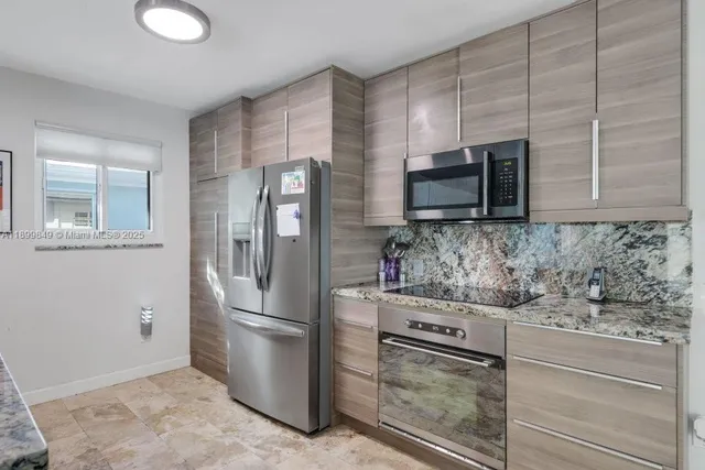 a kitchen with stainless steel appliances granite countertop a refrigerator and a stove