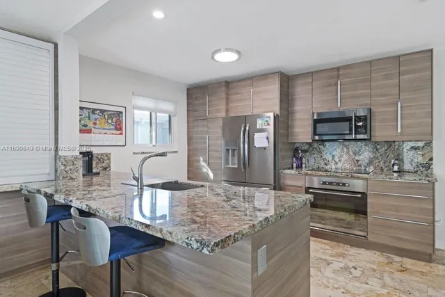 a kitchen with kitchen island granite countertop a stove top oven a sink dishwasher a dining table and chairs with wooden floor