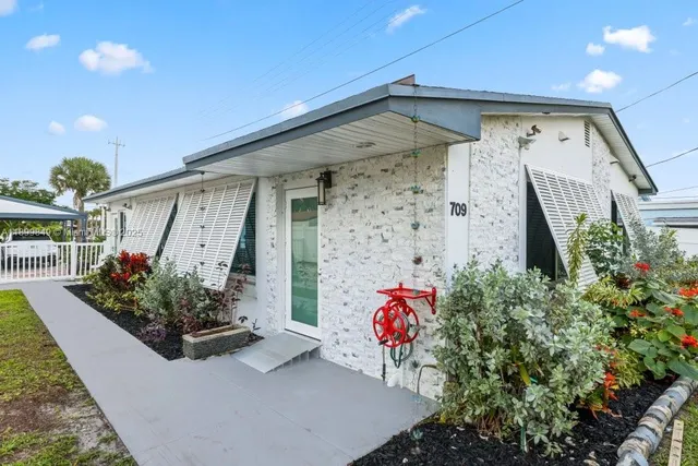 a front view of a house with lots of flowers