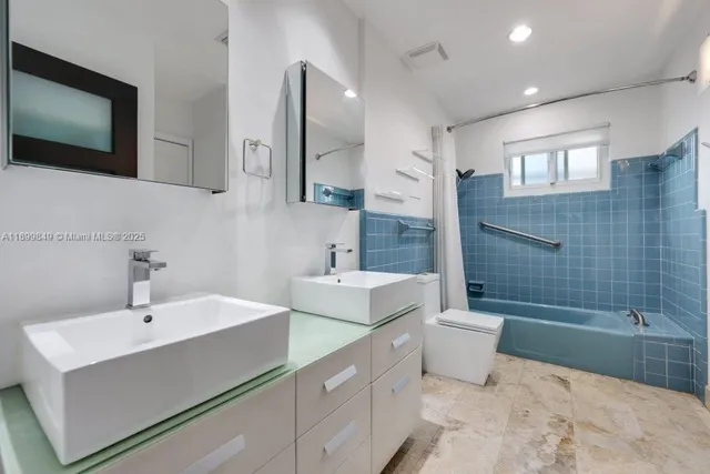 a bathroom with a double vanity sink toilet mirror and bathtub
