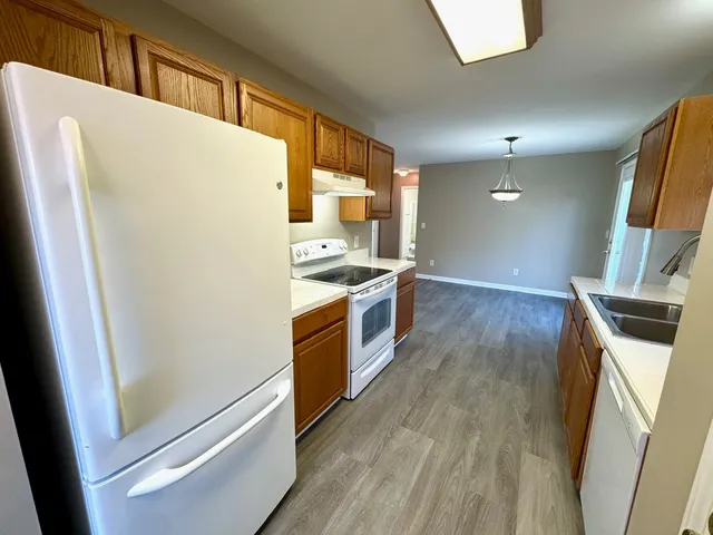 a kitchen with stainless steel appliances a refrigerator a sink a stove and white cabinets with wooden floor