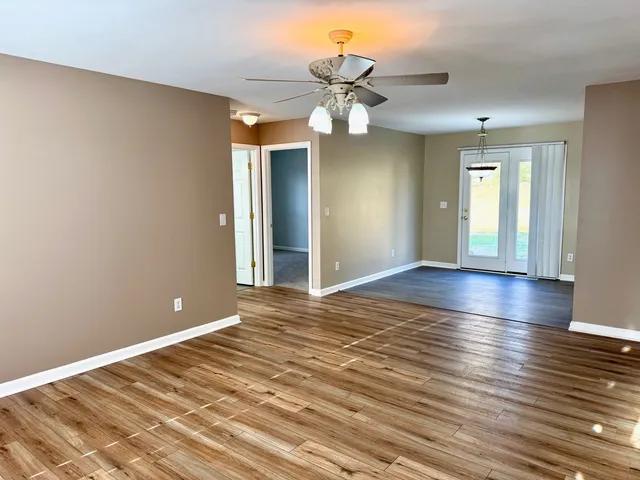 a view of an empty room with window and wooden floor