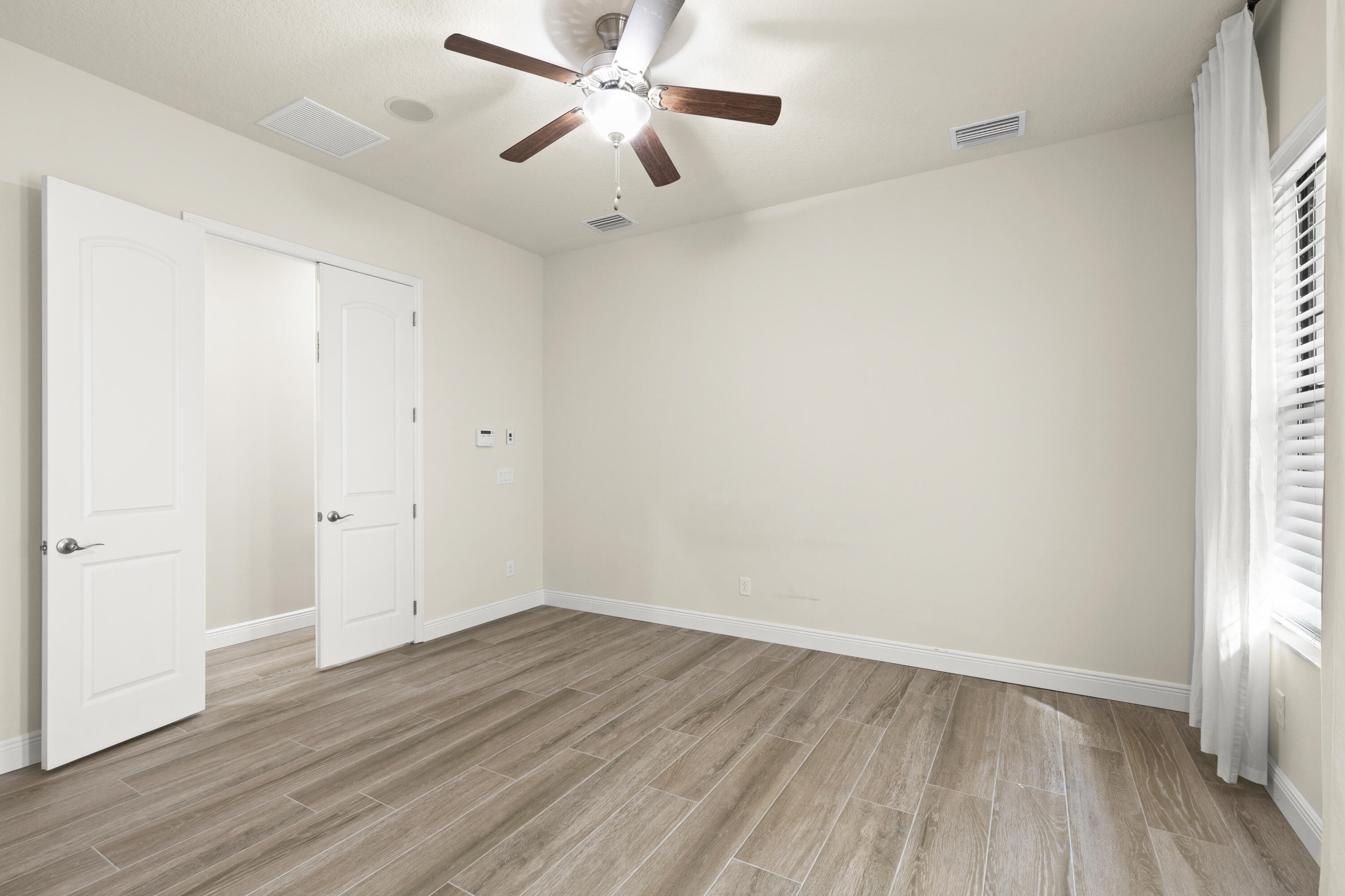 7065 Primavera Lane Melbourne, FL 32940 - Photo 13 of 40 an empty room with wooden floor and windows