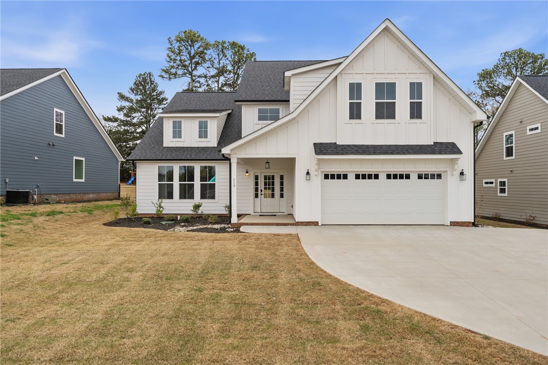 This newly constructed residence presents a modern farmhouse aesthetic with a spacious driveway.