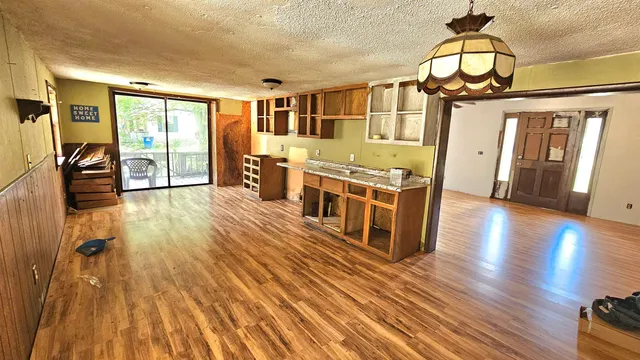 a living room with stainless steel appliances wooden floors and kitchen view