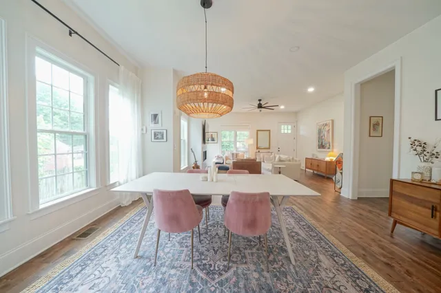 a view of a dining room and livingroom with furniture wooden floor a rug a flat screen tv a rug a fireplace and a chandelier