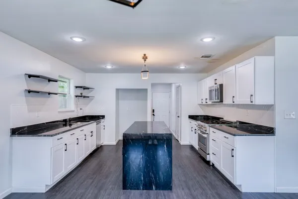 a kitchen with stainless steel appliances a stove and wooden floor