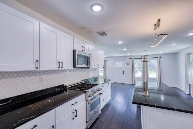 a kitchen with stainless steel appliances granite countertop a sink a stove and a wooden floors