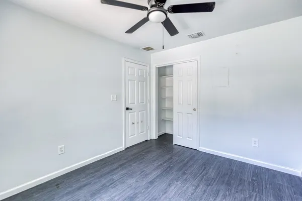 a view of a room with wooden floor a ceiling fan and window