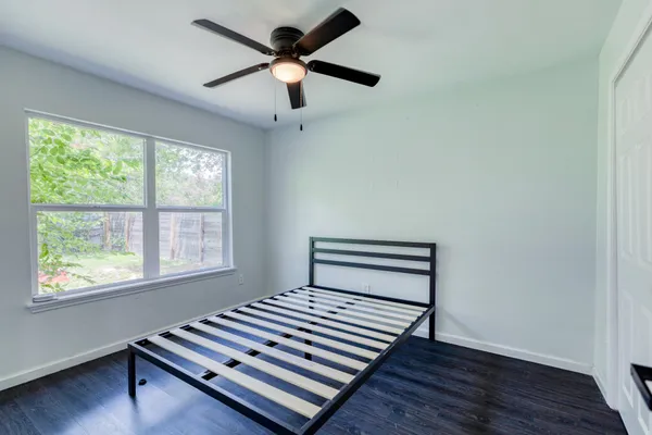 an empty room with wooden floor a ceiling fan and windows