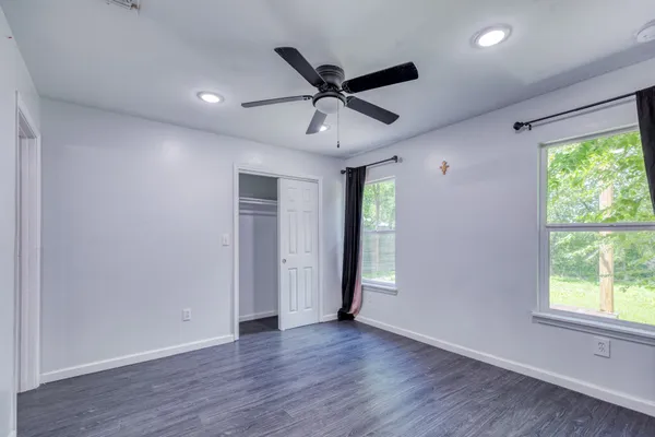 a view of an empty room with wooden floor and a window