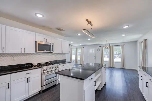 a kitchen with granite countertop a sink cabinets and wooden floor
