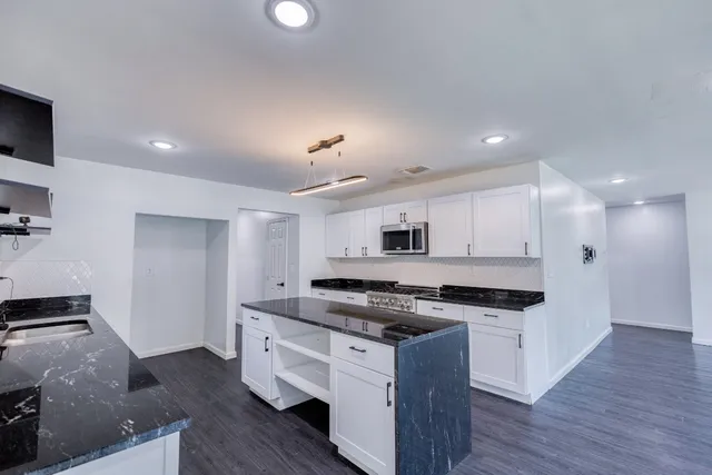 a kitchen with stainless steel appliances granite countertop a stove a sink and a refrigerator