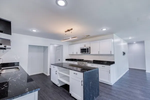 a kitchen with stainless steel appliances granite countertop a stove a sink and a refrigerator