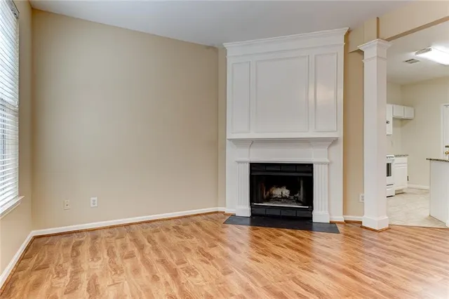 a view of an empty room with wooden floor fireplace and a window