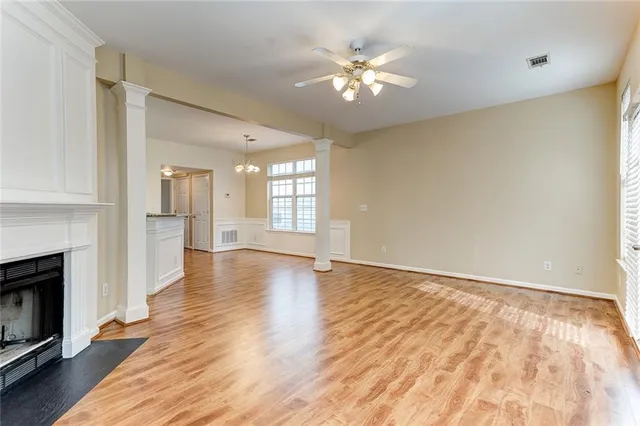 a view of an empty room with wooden floor and a kitchen