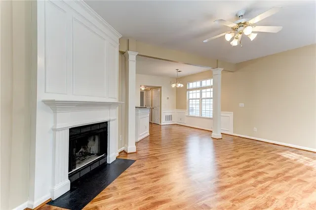 a view of an empty room with chandelier fan and fire place