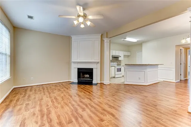 a view of kitchen and empty room with wooden floor and fan