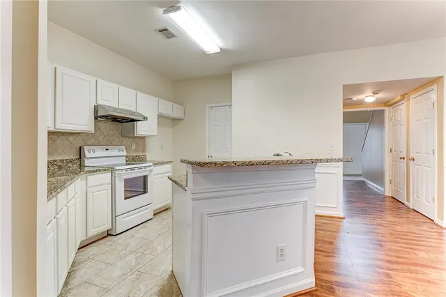a kitchen with granite countertop white cabinets and white appliances