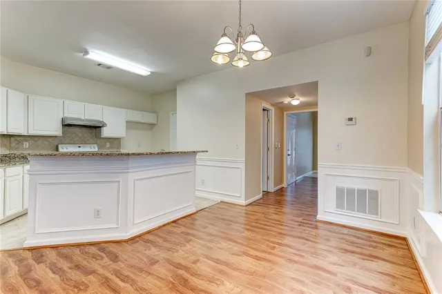 a white kitchen with granite countertop stainless steel appliances a stove and white cabinets