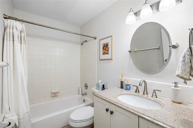 a bathroom with a granite countertop sink mirror toilet and bathtub