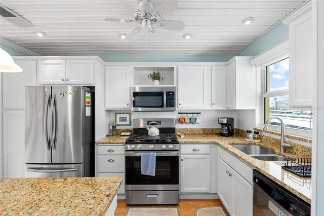 a kitchen with stainless steel appliances granite countertop a refrigerator a stove and a sink with wooden floor