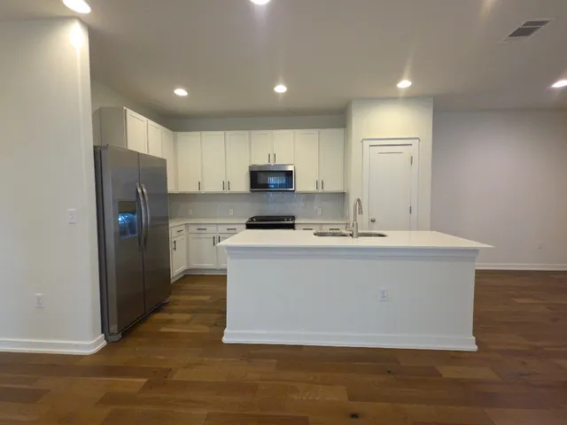 a view of kitchen with stainless steel appliances granite countertop a stove a refrigerator a sink a microwave and with wooden cabinets