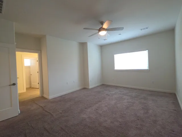 an empty room with windows and fan